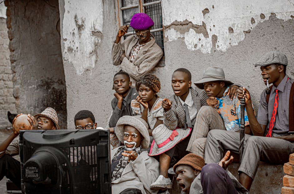 A group of people in vintage attire enjoying outdoor TV viewing in Malawi.