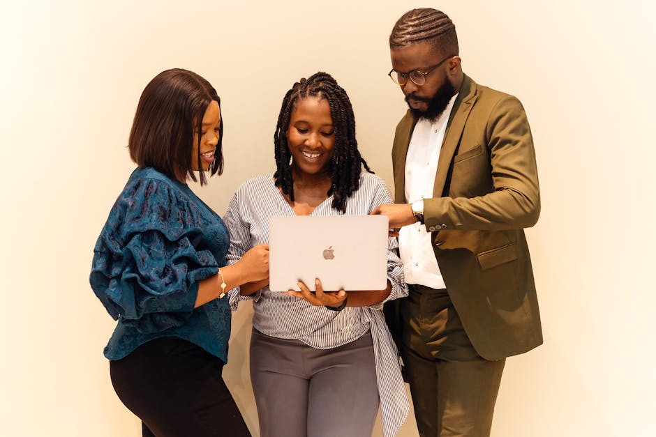 Three professionals collaborating on a project with a laptop in a modern office.