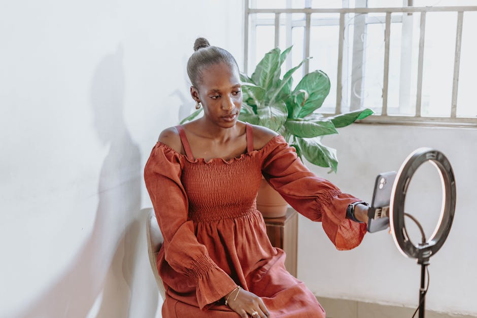 Fashionable woman vlogging indoors with ring light and phone in Abuja, Nigeria.