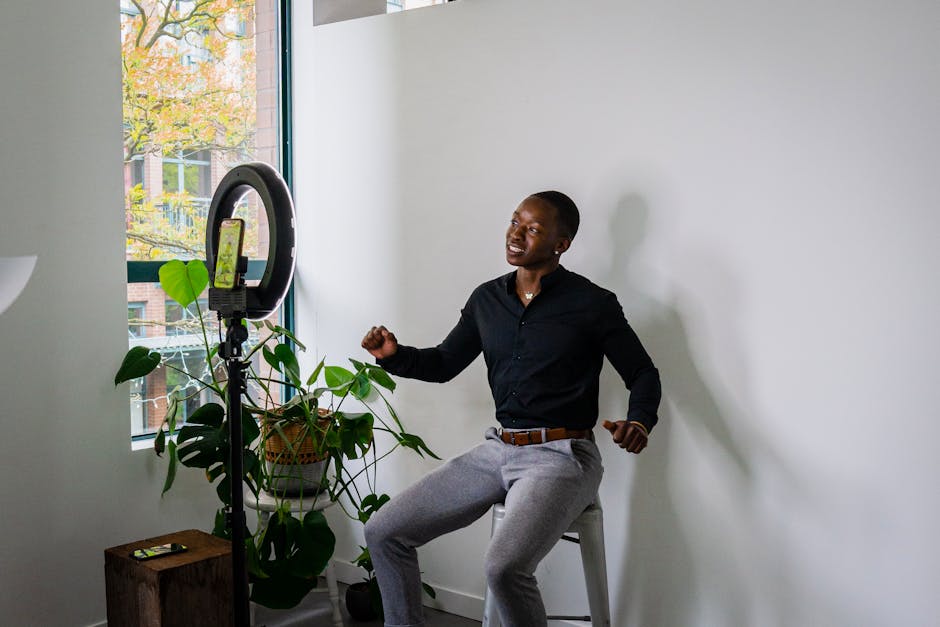 African American man recording a video with a smartphone and ring light in a modern room.