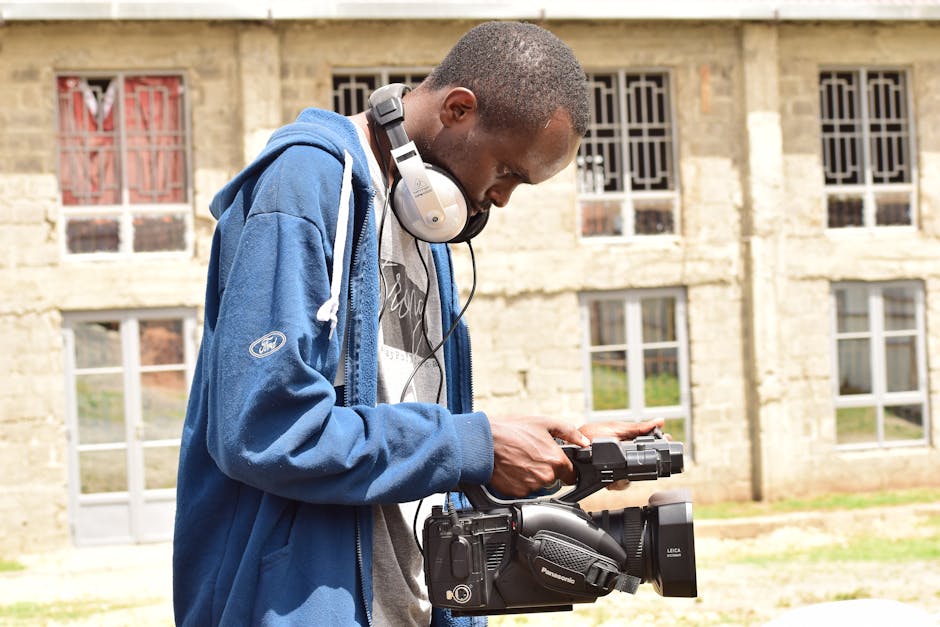 African man using video camera and headphones outdoors in Nairobi, Kenya.