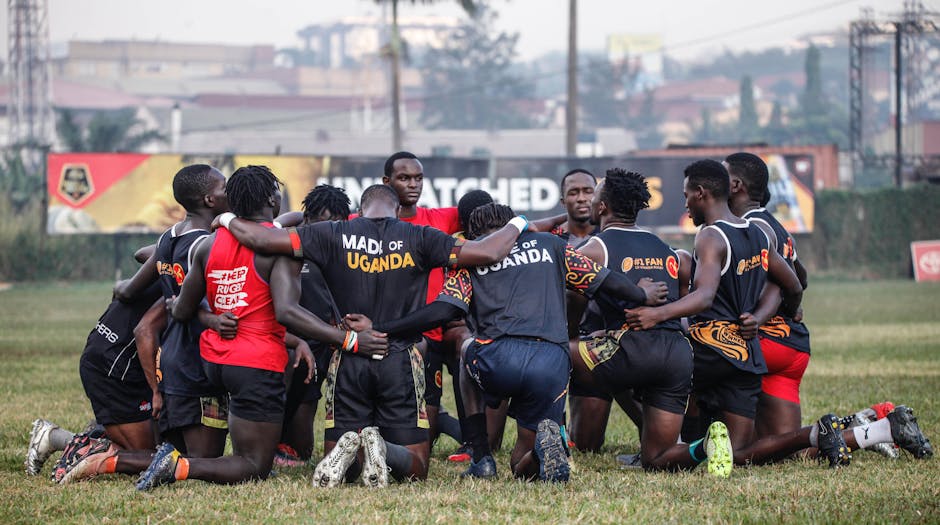 Rugby players kneeling together forming a huddle on a field, highlighting teamwork and unity.