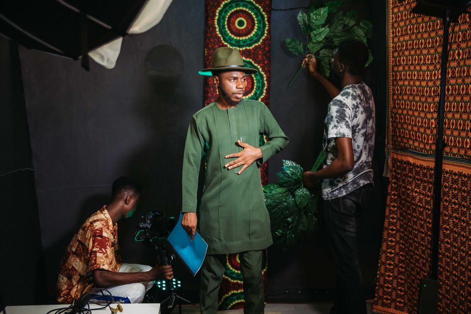A backstage look at a fashion photoshoot with men in traditional green attire, creating a vibrant setup.