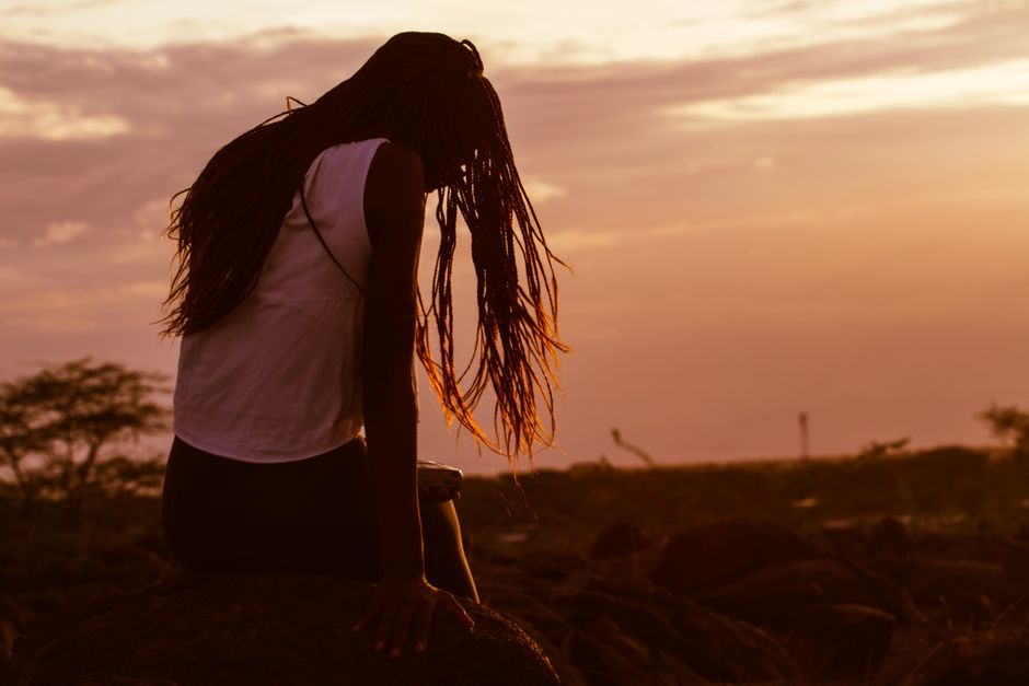 Silhouette of a woman sitting on rocks during a vibrant sunset in Lodwar, Kenya.
