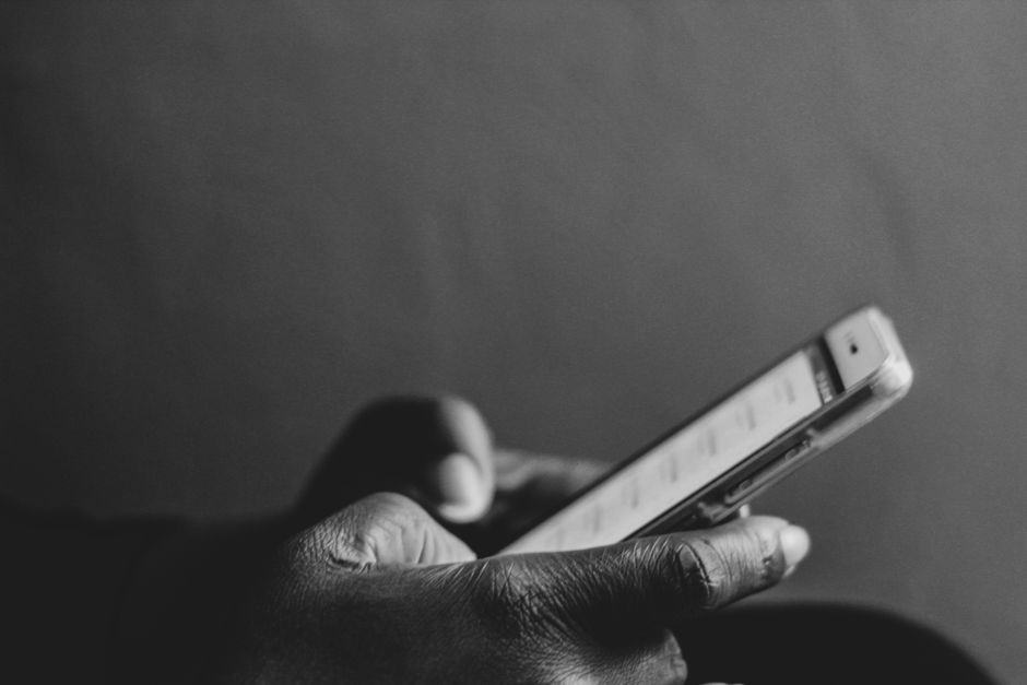 A monochrome image showing a person using a smartphone, emphasizing modern technology.