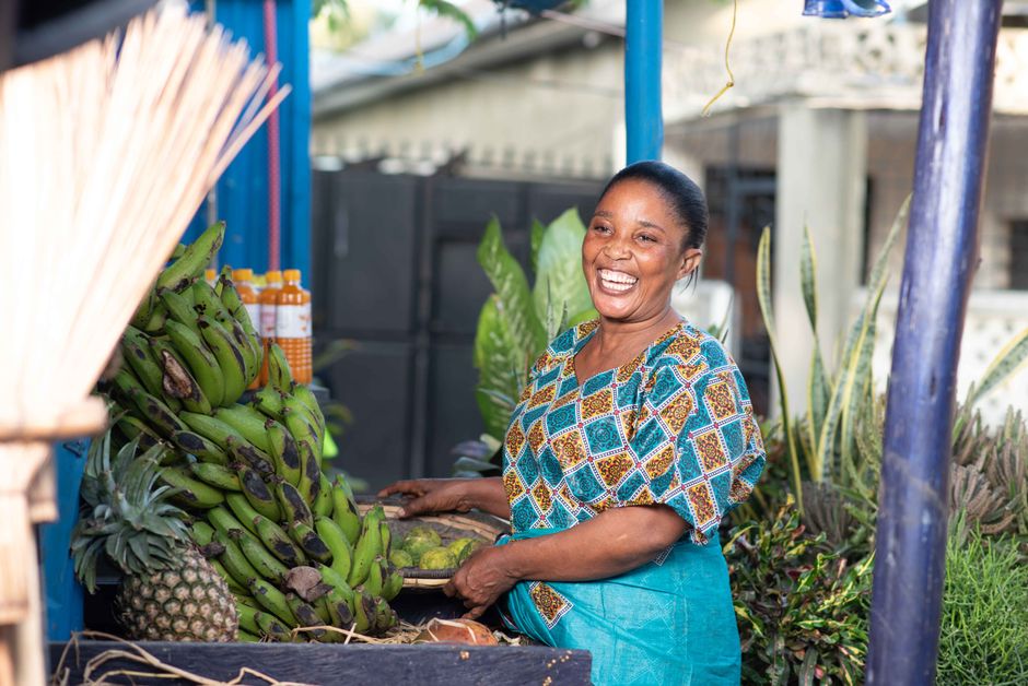 A joyful vendor selling fresh bananas and pineapples at a local market in Dar es Salaam, Tanzania.